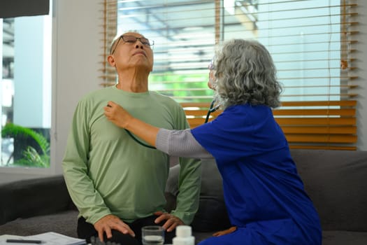 Female doctor listening to patient heartbeat during home visit. Health care concept.