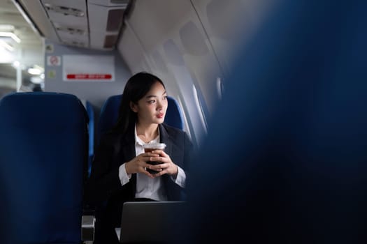 Beautiful Asian businesswoman working with laptop and mobile in aeroplane. working, travel, business concept.