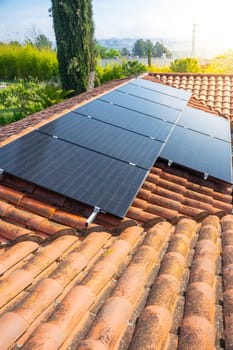 A row of solar panels made of composite material is installed on the sloped roof of a house, harnessing solar power under the sunny sky. High quality photo
