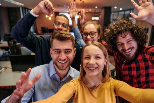 A diverse group of business professionals take a break from their tasks in a modern startup office to capture a creative selfie, showcasing teamwork and a vibrant workplace culture.