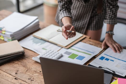 Close-up view of Asian businesswoman working online and planning financial calculation data working from home. Businesswoman and business planner concept.