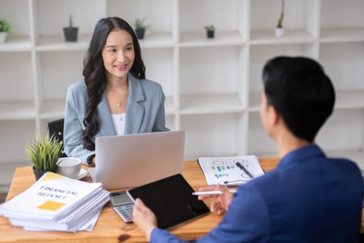 A young businessman and a female Asian accountant are discussing financial accounting and business planning together in the office..