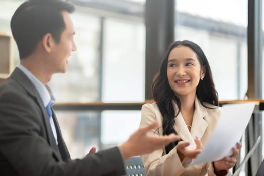 A young businessman and a female Asian accountant are discussing financial accounting and business planning together in the office..