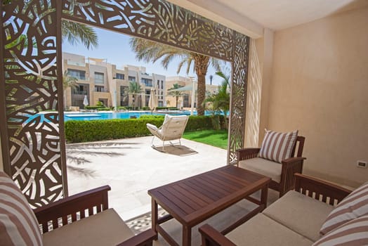 Garden patio terrace of a luxury apartment home in tropical resort with furniture and swimming pool view