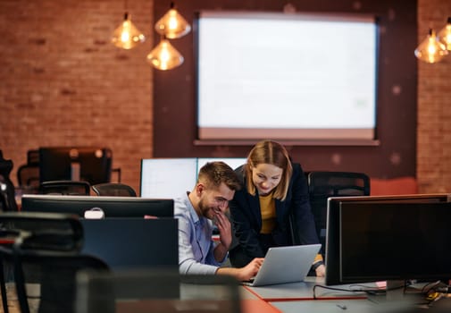 Business colleagues, a man and a woman, engage in discussing business strategies while attentively gazing at a computer monitor, epitomizing collaboration and innovation.