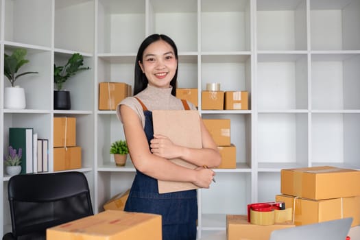 Confident owner of a small online sales business stands holding a clipboard with inventory and shipping information in his home office. Small entrepreneurs prepare to deliver to customers..