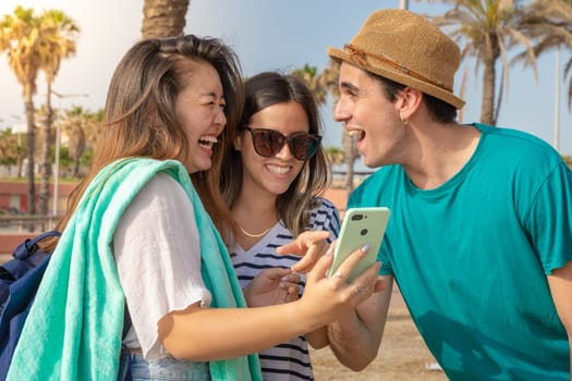 Multicultural group of trendy young friends laughing looking the smartphone. High quality photo