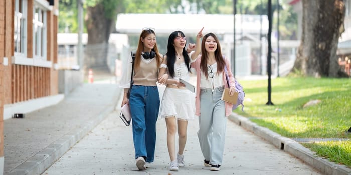 College friends walk to class together. University student in campus talk and have fun outdoors.