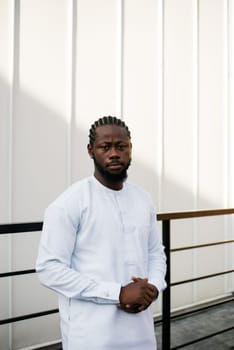 Cheerful male tourist dress in white wear dashiki ethnic smiling at city street on stairs. African American travel model have free time.