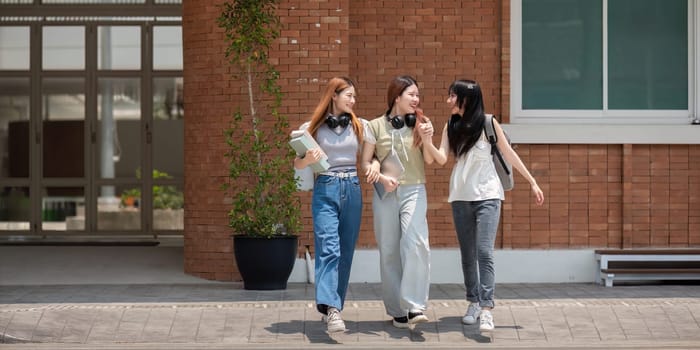 College friends walk to class together. University student in campus talk and have fun outdoors.