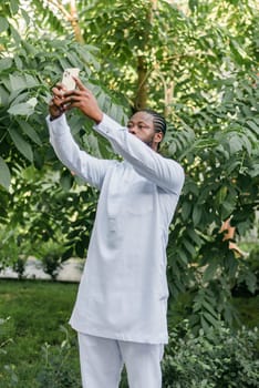 Happy young African American man in dashiki ethnic clothes taking selfie on brick wall background. Millennial generation student and youth