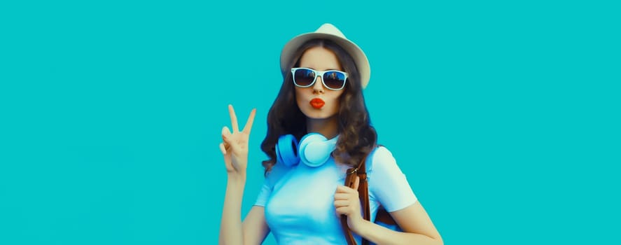 Happy modern happy young woman listening to music with headphones on blue studio background