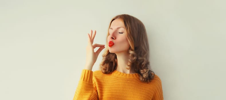 Portrait of happy young woman enjoying perfect flavor, shows gesture of delicious taste of food on studio background