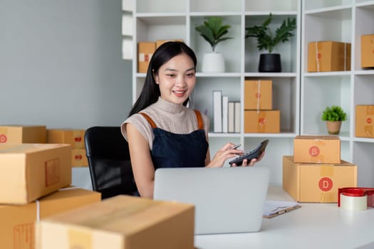 Young business woman asian working online ecommerce shopping at her shop. Young woman sell prepare parcel box of product for deliver to customer. Online selling.