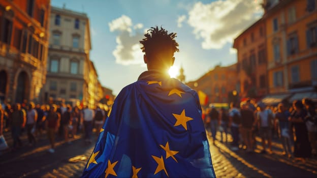 A young man with a European Union flag on his shoulders walks along the street of a European city.