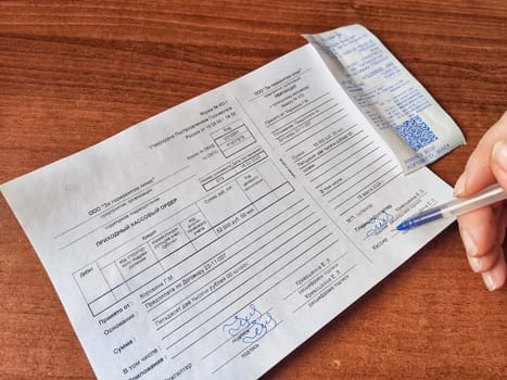 Kirov, Russia - March 18, 2024: Close-up of hand with a pen signing a paper document. Hand Signing an Official Document on a Wooden Table