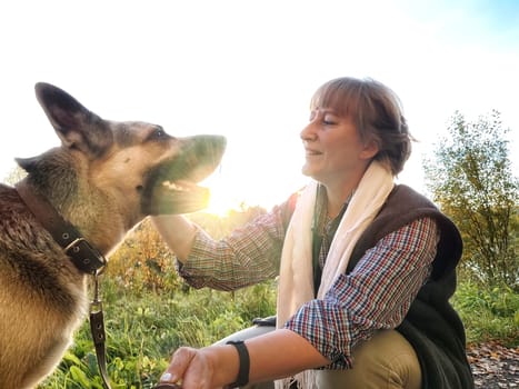 Adult girl with shepherd dog taking selfies in village. Middle aged woman and big shepherd dog on nature. Friendship, love, communication, fun, hugs