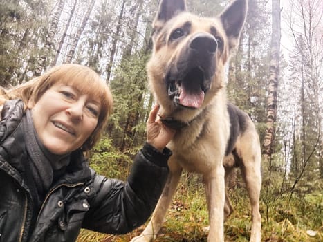 Adult girl or middle aged woman with shepherd dog in an autumn day