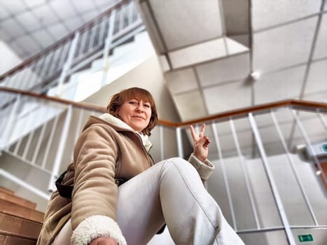 Cute girl on Indoor Staircase. Mature middle aged woman taking selfie indoors