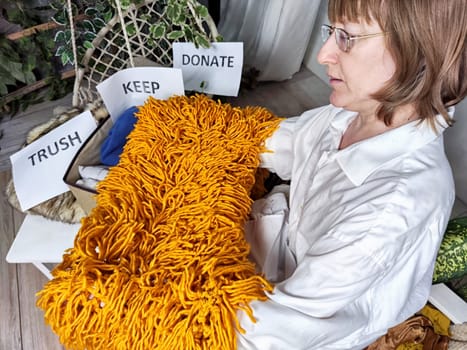 Middle-Aged Woman Sorting Belongings With KonMari Method. Mature woman categorizes items into keep and discard piles