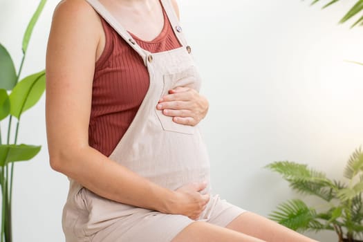 Pregnant woman embracing belly in living room with copy space for text. High quality 4k footage