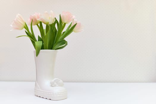 bouquet of tulips in Easter bunny vase on white table. copy space