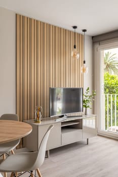 A modern TV space with unique wooden wall decor and elegant light fixtures, creating a warm atmosphere.