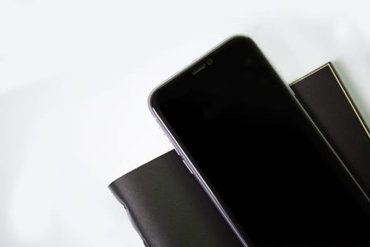 phone with black textured notebook on a white background. View from above.