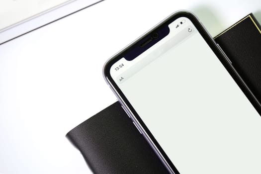 phone with black textured notebook on a white background. View from above.