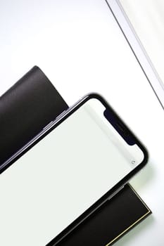 smartphone with black leather notebook on white background. View from above.