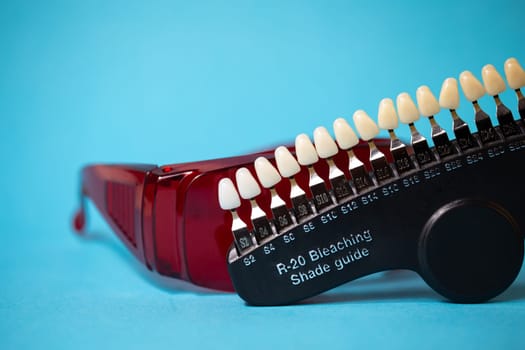 Dental equipment for the selection of the shade and color of teeth in close-up on a blue background.