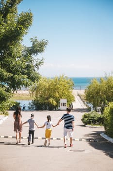 family walking towards the sea view from the back.