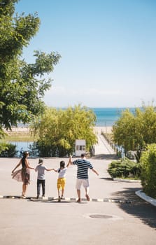 happy family goes to the side of the sea in summer. back view.