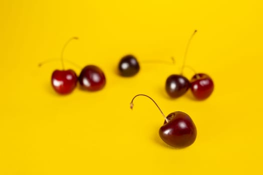 ripe summer cherries on a yellow background.