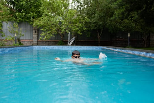 a boy swims in the summer in the pool in the yard.