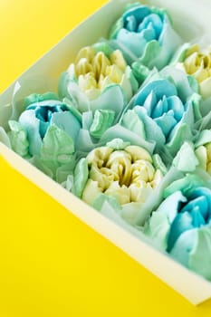 Box of colorful desserts in the shape of flowers on a two-color background. Marshmallow in the form of a rose