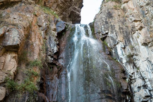 a high waterfall among rocky mountains a waterfall with a strong stream flows. Outdoor landscape. Tourism