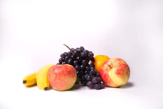 Still life of fruits on a white background, banana, apple, grapes.