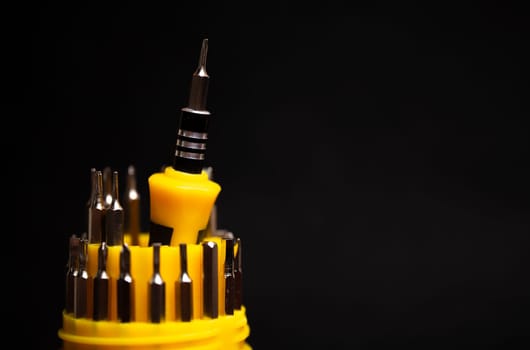 a set of yellow screwdrivers on a black background.