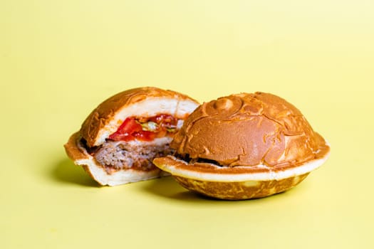 The round waffle sandwich buns have a golden-brown color and are filled with a beef patty, tomato, cheese, and lettuce.