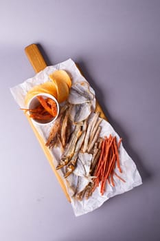 A variety of dehydrated fish, carrots, and pumpkin slices on a white paper over grey background. Isolated on a grey background.