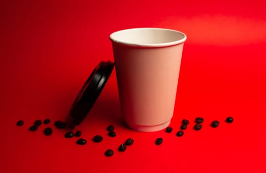 paper coffee cup with coffee beans on a red background