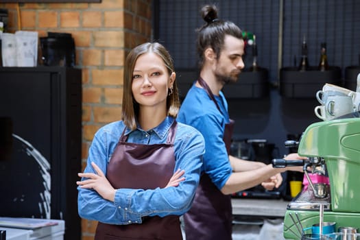 Business team colleagues partners young man woman in aprons working together in workplace behind counter in restaurant coffee shop cafeteria. Cooperation staff partnership teamwork work small business