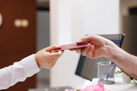 Close-up shot of caucasian pair of hands grasping passport for check-in verification procedure. In hotel reception, senior man handing his personal document to concierge for reservation.