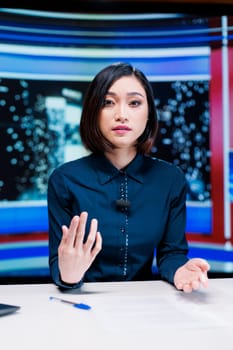 Reporter on night talk show presenting events during entertainment and media segment in newsroom. Woman journalist discussing about breaking news reportage with exclusive headlines.