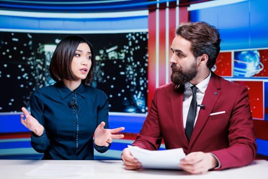 Diverse broadcasters reading daily headlines in newsroom, using media outlets papers to present latest information and updates about events. Journalists team reporting live for tv newscast.