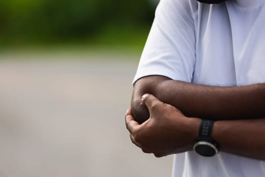 Close up Asian young sport runner black man wear watch he having elbow pain and use hands joint hold elbow while exercising at the outdoor street health park, healthy exercise Injury from workout
