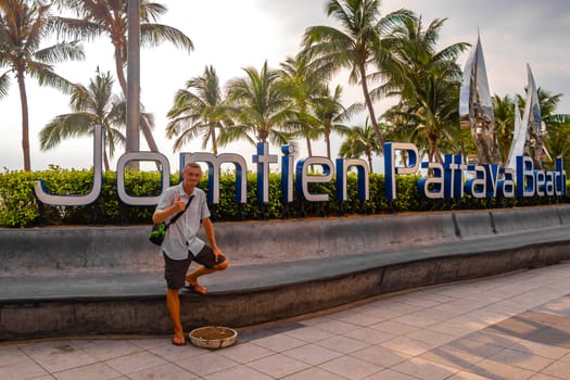 Male tourist young man at Jomtien and Dongtan Pattaya lettering name welcome city sign in Pattaya Bang Lamung Amphoe Chon Buri Thailand in Southeastasia Asia.