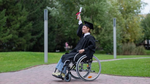Caucasian woman in a wheelchair in a graduate costume rejoices at receiving a diploma