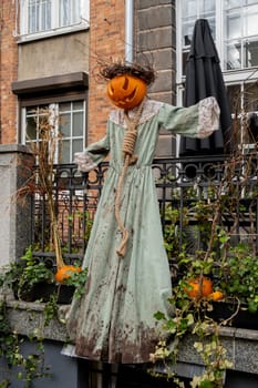 Exterior Beautiful atmospheric halloween scary scarecrow pumpkin decorated on porch. Autumn leaves and fall flowers celebration holiday Thanksgiving October season outdoors in city